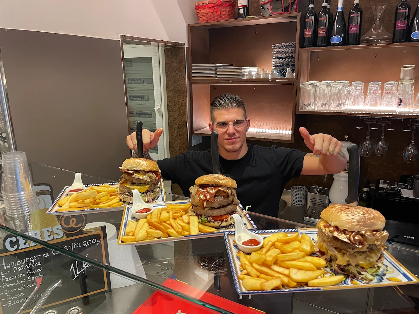 Il nostro chef al bancone con tre maxi panini doppi e patatine