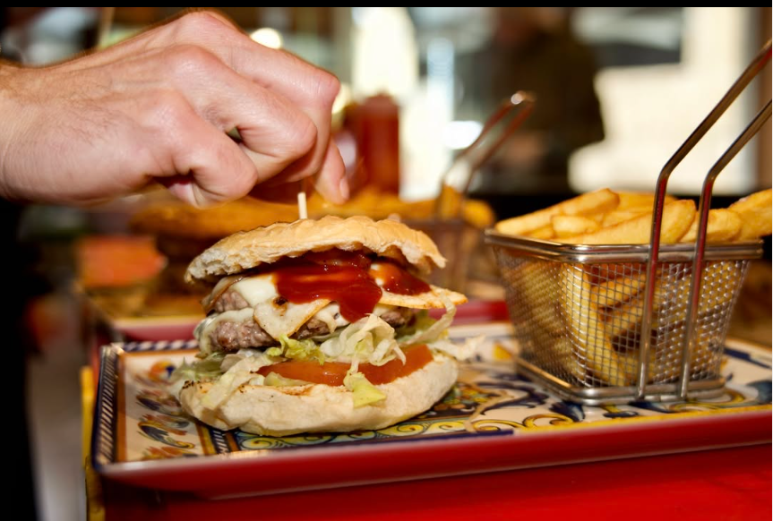 Doppio hamburger con uovo e patatine fritte su vassoio rosso