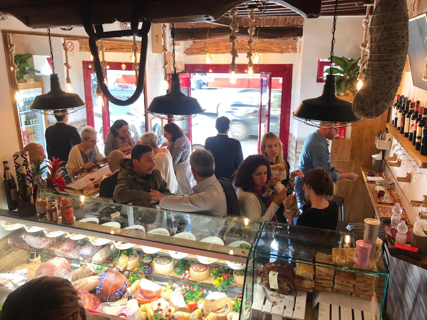 Il locale pieno di clienti tra banco salumi e luci calde
